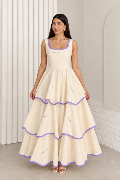Model wearing cream sleeveless tiered maxi dress with purple contrast trim